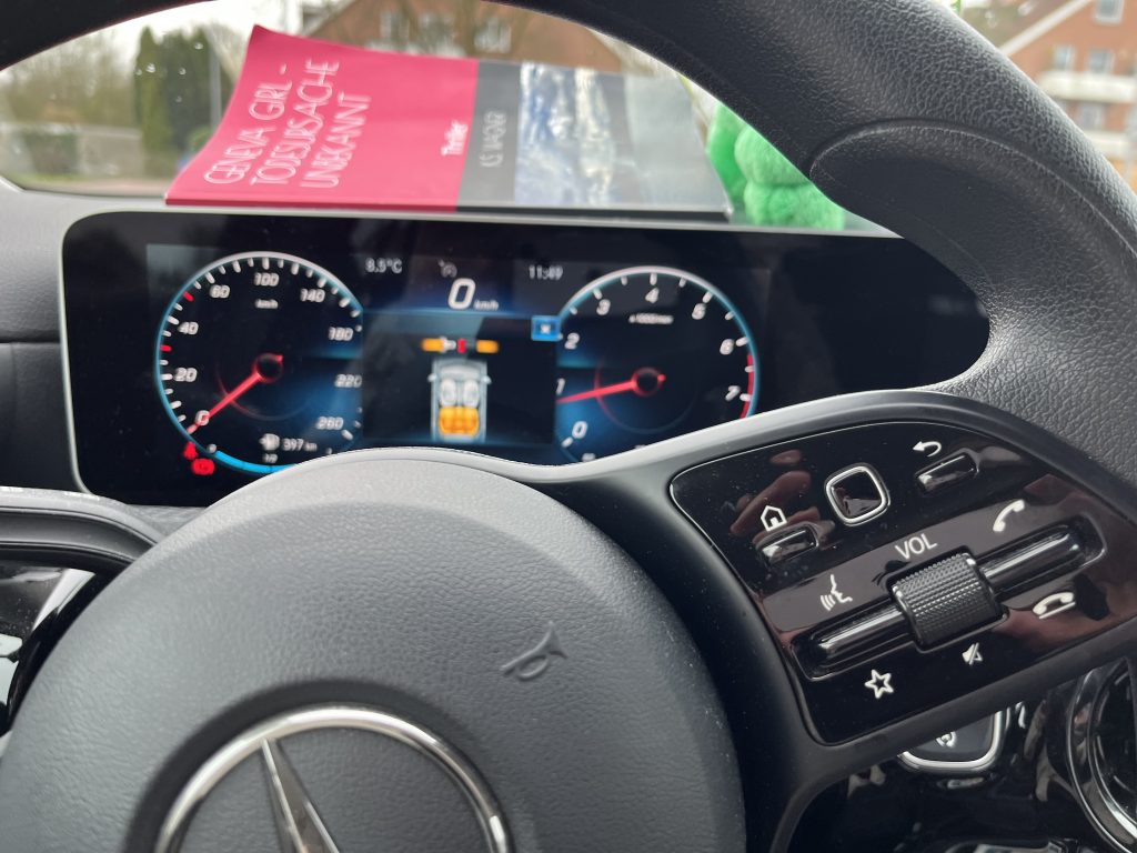Mercedes Cockpit mit Taschenbuch Geneva Girl - Todesursache unbekannt
